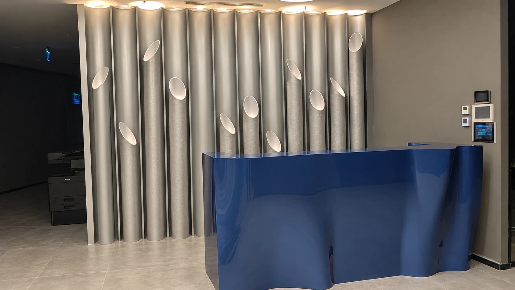 Blue sculptural reception counter in front of silver-grey vertical wall elements